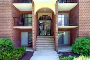 Un edificio de ladrillo de dos pisos con una entrada central, una escalera y balcones en cada nivel.