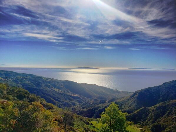 A panoramic view of a coastal landscape with a clear sky, a body of water, and green hills. - Spectacular Malibu Ocean & Mountain View Villa with no cleaning list! (Malibu)
