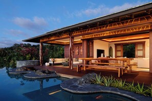 Une maison moderne dotée d’une piscine, d’une terrasse en bois et d’un espace salon extérieur.