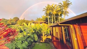 Une maison avec un jardin et un arc-en-ciel en arrière-plan.