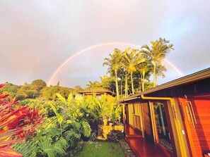 A house with a garden and a rainbow in the background.