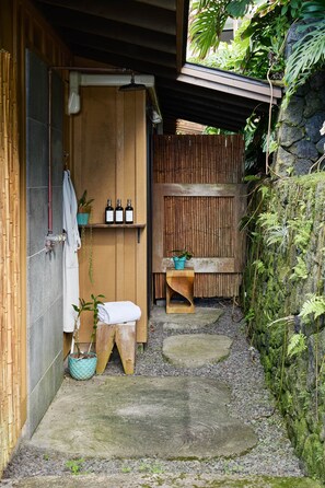 A wooden spa area with a wooden bench, a towel, and a small table with bottles. - Holualoa Sanctuary Hot Tub, Ocean Views, A/C 12 Min to Beach (Honalo)