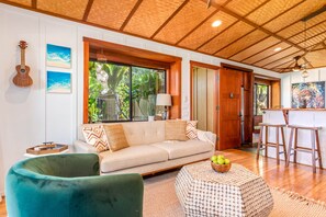A living room with a sofa, a green armchair, a coffee table, and a dining area with bar stools. - Holualoa Sanctuary Hot Tub, Ocean Views, A/C 12 Min to Beach (Honalo)