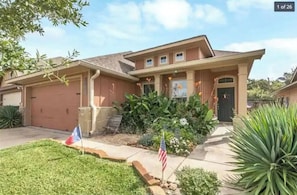 A residential house with a garage, a front porch, and a well-maintained lawn.