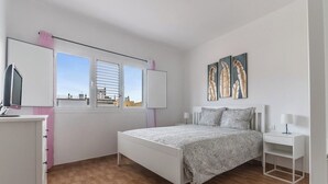 A bedroom with a bed, a desk, a chair, a window with blinds, and artwork on the wall. - Home2Book Charming Attic Arucas Center, Terrace (Arucas)