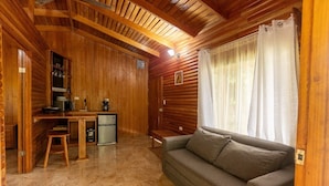 A cozy log cabin interior with a wooden dining table, a sofa, and a small kitchenette.