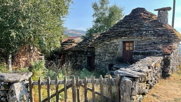 A stone cottage with a wooden door, surrounded by a stone fence and trees. - Casa do Desassossego  (Monção)