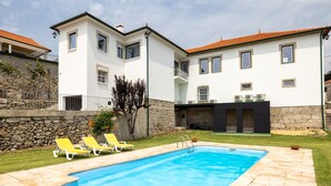 A swimming pool with a stone border, two yellow lounge chairs, and a stone wall. - Casa do Desassossego  (Monção)
