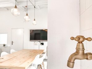 Un interior moderno con una mesa de comedor de madera, lámparas colgantes y un televisor montado.