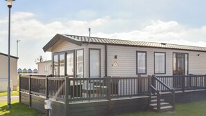 Une maison mobile de plain-pied dotée d’une terrasse clôturée et d’un escalier menant à l’entrée.