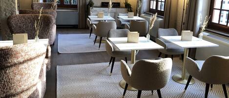 A cozy restaurant interior with wooden beams, tables, and chairs.