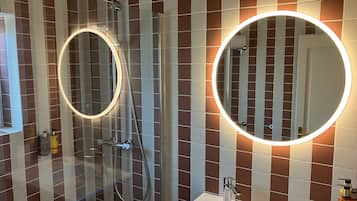 A bathroom with a shower, a sink, and two illuminated mirrors.