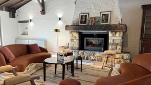 Una sala de estar acogedora con chimenea de piedra, asientos cómodos y un televisor.