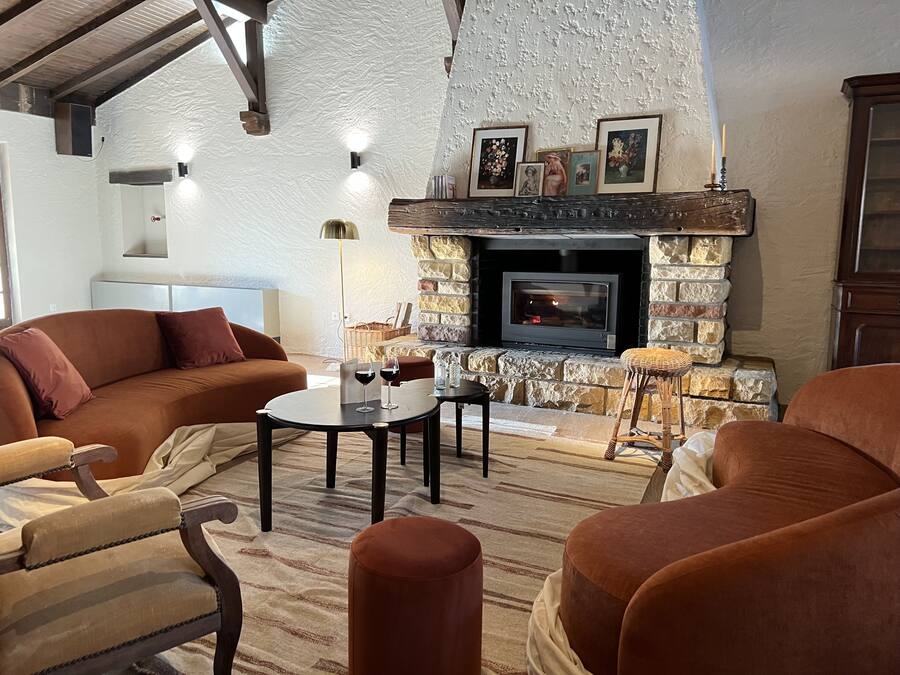 A cozy living room with a stone fireplace, comfortable seating, and a television.