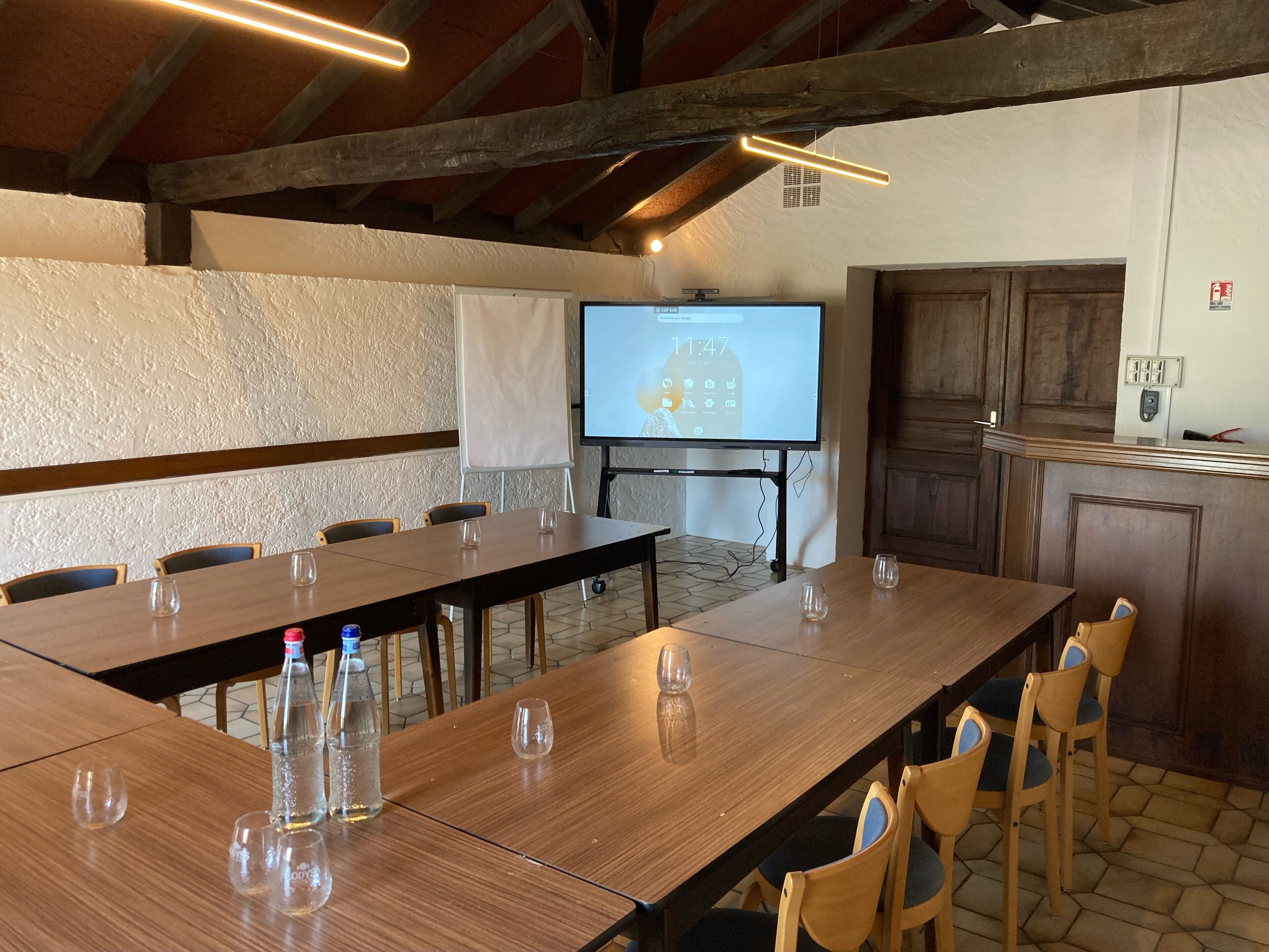 A conference room with a long table, chairs, a projector screen, and a whiteboard.