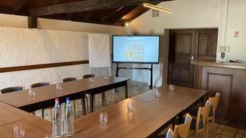 A conference room with a long table, chairs, a projector screen, and a whiteboard.