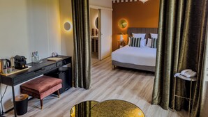 Habitación de hotel con cama, escritorio y baño visible a través de una cortina.