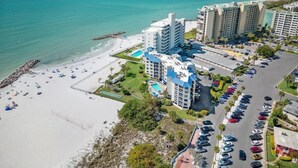 A coastal hotel with multiple high-rise buildings, a beach with sun loungers, and a parking area. - Stunning beachfront views on St. Pete Beach (St. Pete Beach)