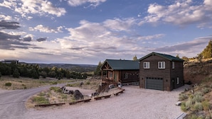 A rustic cabin with a gravel driveway and a covered porch, surrounded by a natural landscape. - Bryce & Zion Midpoint w/ Memorable Cowboy Hot Tub (Alton)