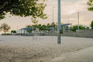 Ein Beachvolleyballfeld mit Netz, einer Leiter und einem überdachten Sitzbereich.
