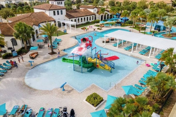 Piscina com tobogã, espreguiçadeiras e palmeiras.