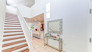 Ein modernes Interieur mit einer Holztreppe, einem Glastischchen und einer geometrischen Wanddekoration.
