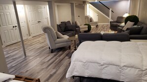 Ein geräumiger Raum mit einem großen Bett, einer Couch und einem Sessel. Eine Treppe führt zu einer erhöhten Ebene.