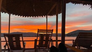 Vista del atardecer desde una terraza techada con sillas de madera.