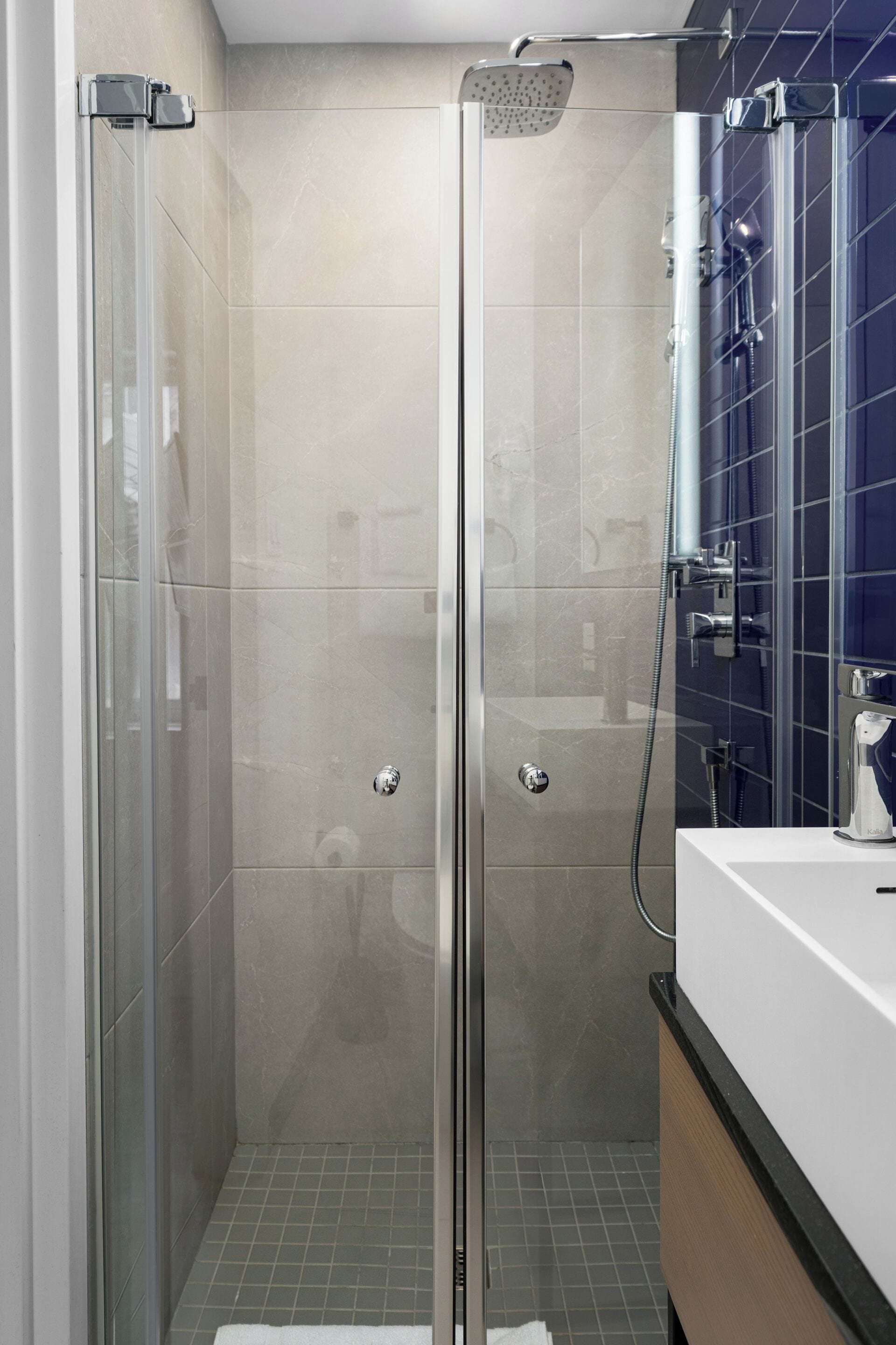 Une cabine de douche fermée par des parois en verre, équipée d’un pommeau de douche à main, d’un autre pommeau de douche à main et d’un troisième pommeau de douche à main.