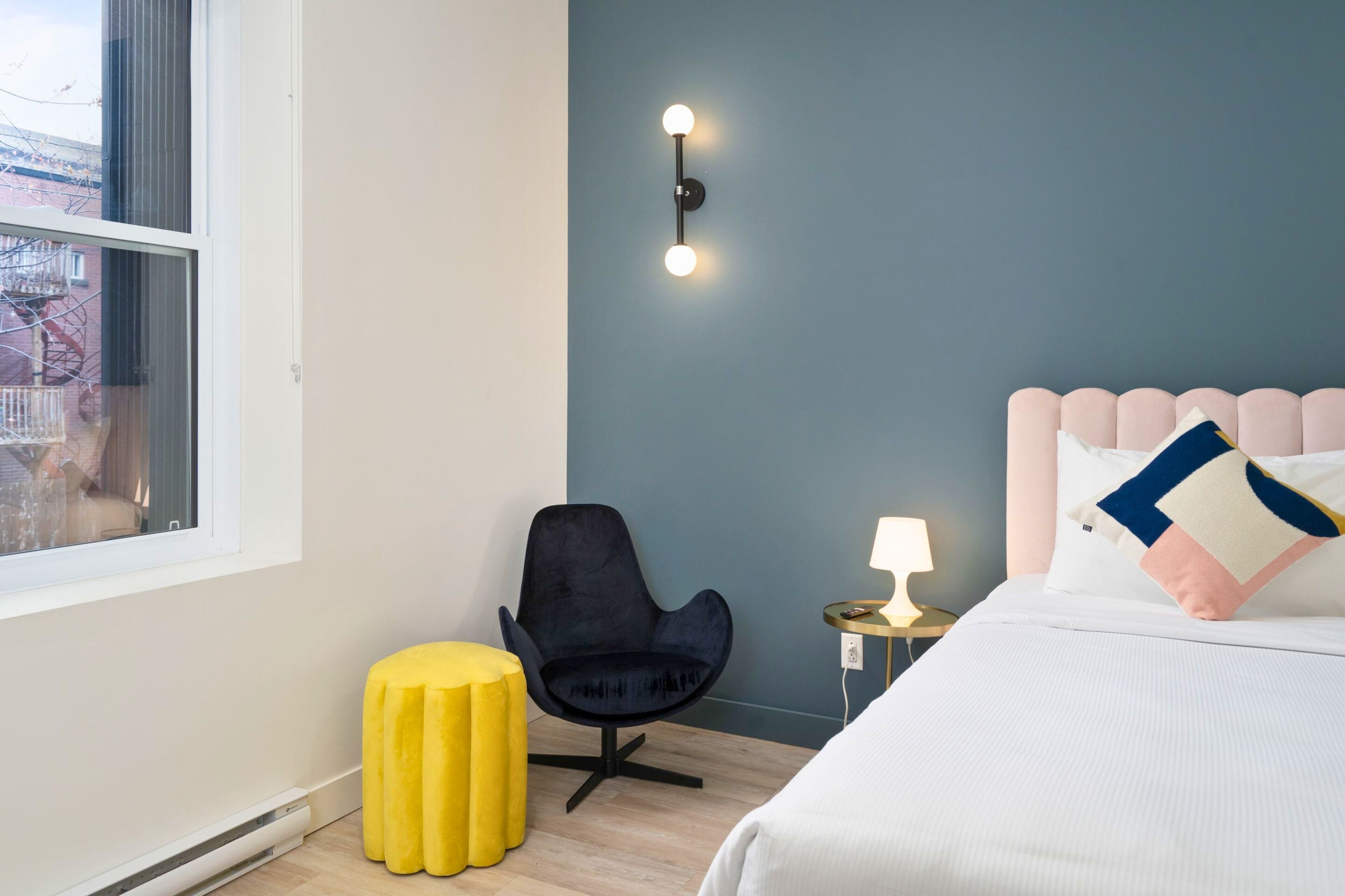 Une chambre d’hôtel avec un lit, une chaise, une petite table et une fenêtre.