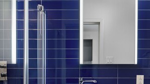 Un baño moderno con cabina de ducha de vidrio, un lavabo blanco y un espejo sobre él.