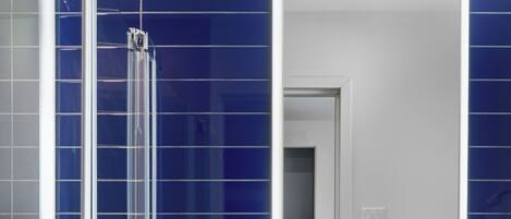 A modern bathroom with a glass shower enclosure, a white sink, and a mirror above it.