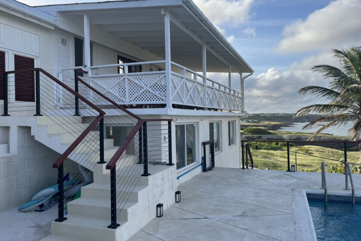 A two-story house with a balcony, a pool, and a view of the landscape.