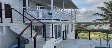 A two-story house with a balcony, a pool, and a view of the landscape.