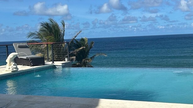 A pool with a clear view of the ocean, a palm tree, and a lounge chair. - 5 bedroom relaxation Oceanfront w/ Stunning natural views.  5 bdrms, sleeps 12 (Marley Vale)