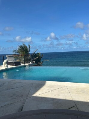 A pool with a clear view of the ocean, a palm tree, and a lounge chair. - 5 bedroom relaxation Oceanfront w/ Stunning natural views.  5 bdrms, sleeps 12 (Marley Vale)