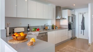 A modern kitchen with white cabinets, a stainless steel refrigerator, and a built-in oven.