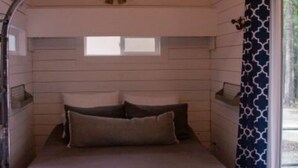 A bedroom with a bed, pillows, a window, and a patterned curtain. - House - The Fais Do Do (Hattiesburg)