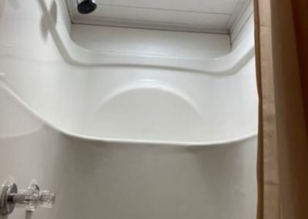Une baignoire blanche au design incurvé, avec un robinet apparent et une pomme de douche.