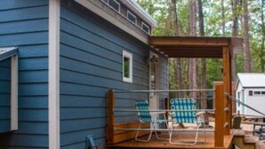 Een blauw huis met een houten terras en twee stoelen.
