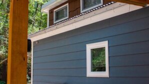 Een huis met een blauwe gevel, een klein raam en een houten constructie erboven.