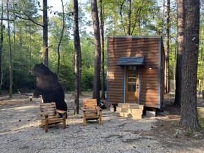Une cabane avec une façade en bois, une porte et un petit porche doté de deux bancs en bois.