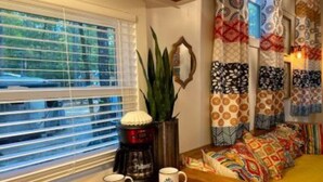 A cozy seating area with a coffee maker, two mugs, and patterned cushions. - Tiny House - Shangri La (Hattiesburg)