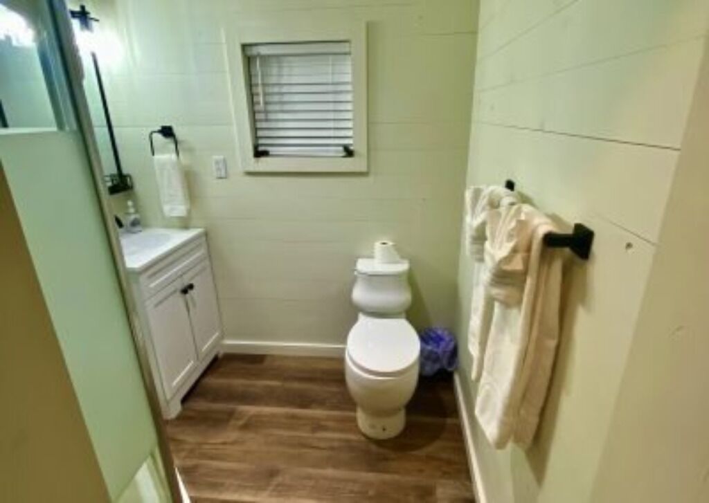 A small bathroom with a toilet, a sink, and a window.