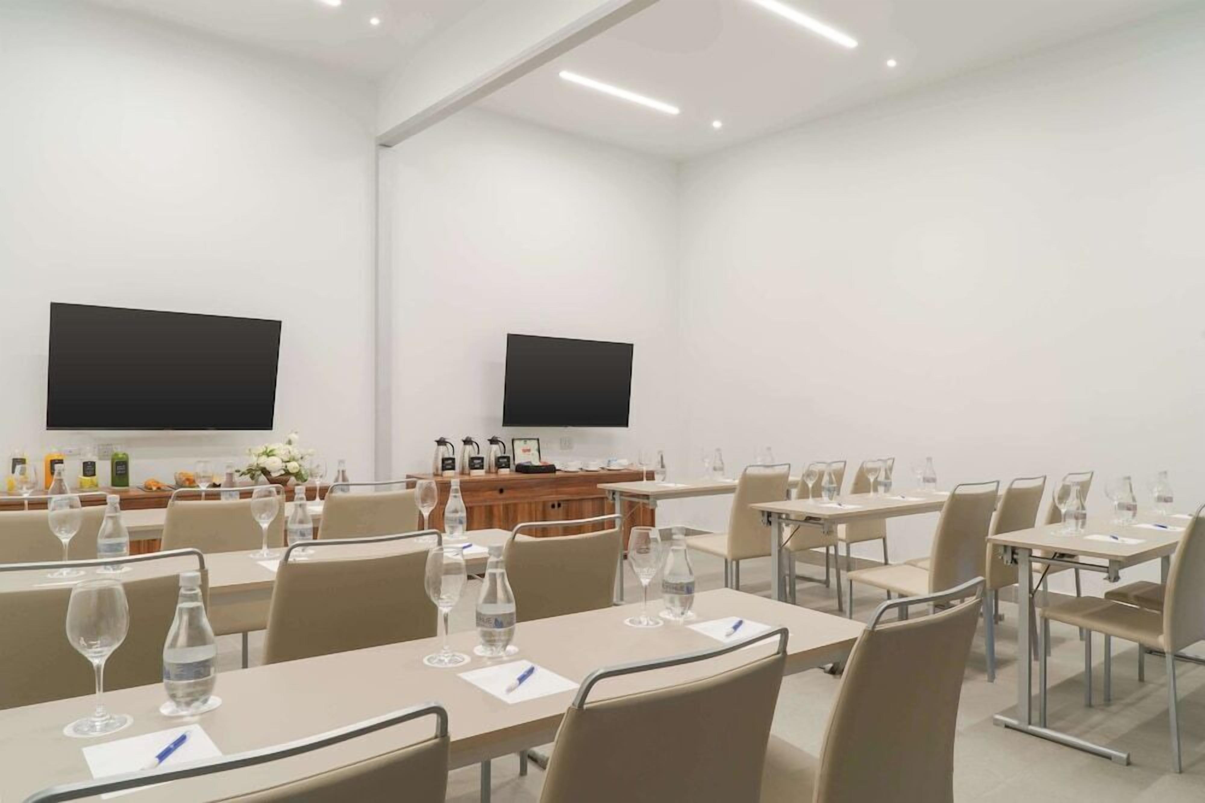 A conference room with tables, chairs, water bottles, and a television screen.