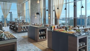A modern hotel dining area with large windows, buffet stations, and contemporary lighting. - NH Iquique Pacifico (Iquique)