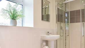 Une salle de bain moderne avec une douche à parois de verre, un lavabo blanc et des toilettes.