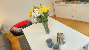 A white table with a vase of yellow flowers, two grey cups, and a silver teapot. - Woodside Retreat, Number 37 (Newbold Coleorton)