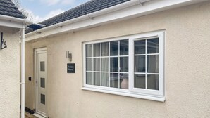 Un edificio de fachada blanca, una puerta con panel de vidrio esmerilado y una ventana con marco blanco.
