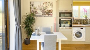 A modern kitchen with a dining table, chairs, a potted plant, and a painting on the wall. - Woodside Retreat, Number 37 (Newbold Coleorton)